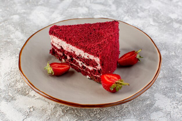 Front close view red cake slice fruit cake piece inside plate with strawberries on the grey surface