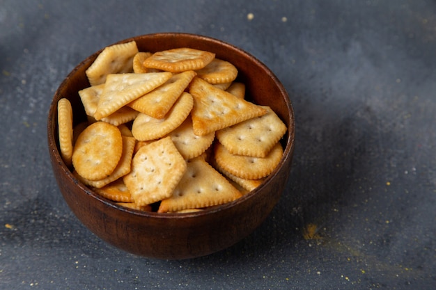 Front close view salted crackers inside brown plate on the grey surface