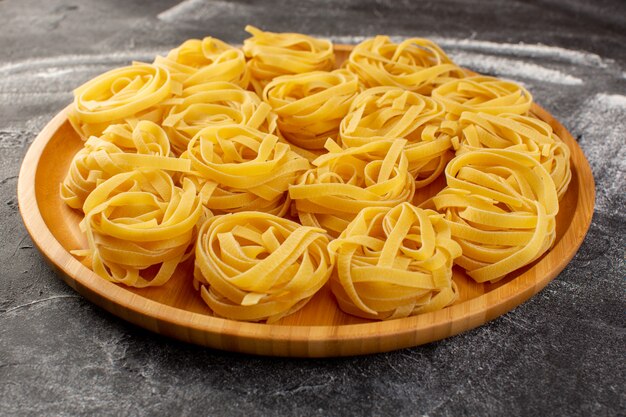 Front close view shaped italian pasta in flower form raw and yellow on the wooden desk