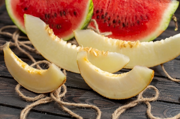 Free photo front close view sliced fresh watermelon half-cut sweet fruit with melon on the brown rustic background