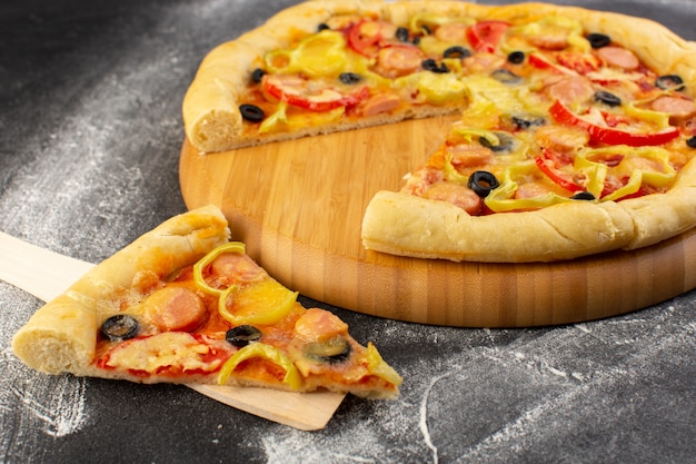 Front close view tasty cheesy pizza with red tomatoes, black olives, bell-peppers and sausages on the dark desk