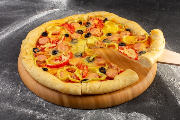 Спереди закрыть вид вкусной сырной пиццы с красными помидорами, маслинами, сладким перцем и колбасками на темной поверхности