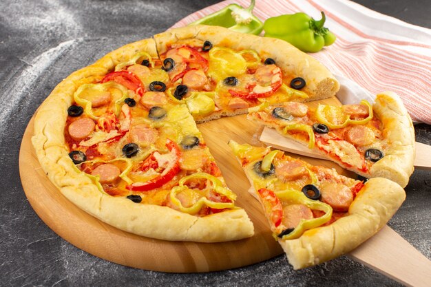 Front close view tasty cheesy pizza with red tomatoes, black olives, bell peppers and sausages on the grey surface