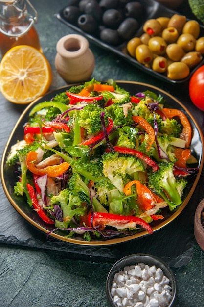 Front close view of vegan salad with fresh ingredients in a plate on black board