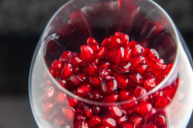 Front close view wine glass with peeled pomegranates inside on dark color fruit wine bar alcohol restaurant red