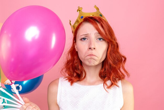 Front close view young female holding colorful balloons on pink desk color party woman photo emotion