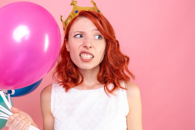 Front close view young female holding colorful balloons on the pink 