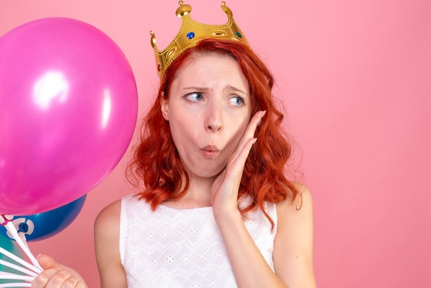 Front close view young female holding colorful balloons worried on pink 