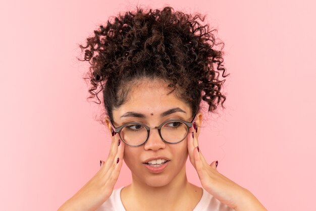 Front close view of young female thinking on pink