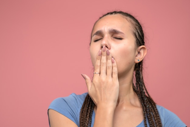 Front close view young girl yawning on pink