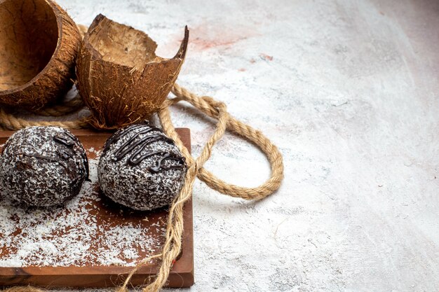 Вид спереди крупным планом вкусные шоколадные торты с кокосом на светло-белой поверхности выпечка бисквитного сахарного торта сладкое печенье шоколадное