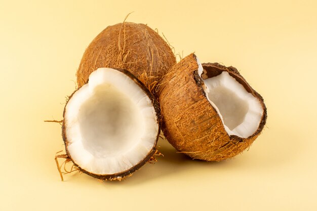 A front closed up view coco nuts sliced milky fresh mellow isolated on the cream colored background tropical exotic fruit nut