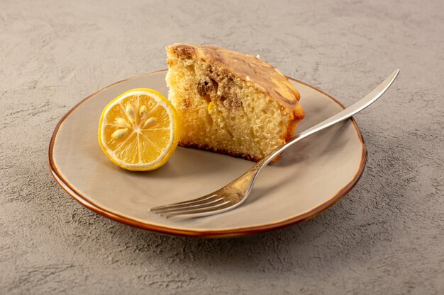 Фронт закрытый вид сладкий кусок торта вкусный вкусный шоколадный торт нарезанный внутри бежевая тарелка с кусочком лимона