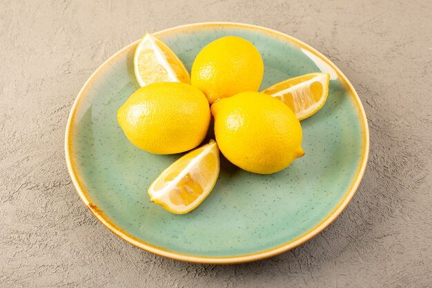 전면보기 노란색 신선한 레몬 잘 익은 부드럽고 육즙 전체를 닫고 회색에 녹색 접시 안에 슬라이스