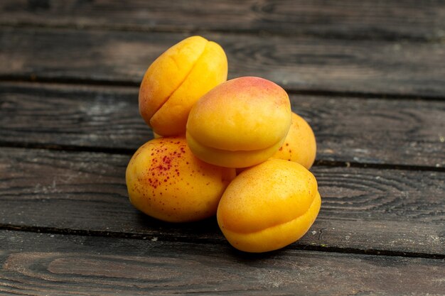 茶色の素朴な背景フルーツビタミン夏に黄色いアプリコットのまろやかで新鮮な果物を正面から見る