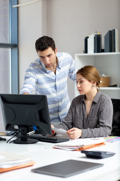 A front distanced view young beautiful lady in grey shirt talking and discussing something with young man inside office during daytime building job activity