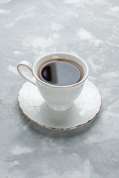 Front distant view cup of tea hot inside white cup on glass plate on light desk