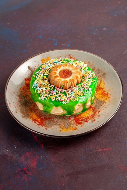 Вид спереди вдалеке маленький вкусный торт с зеленым кремом на темной поверхности печенье бисквит сладкий сахарный пирог