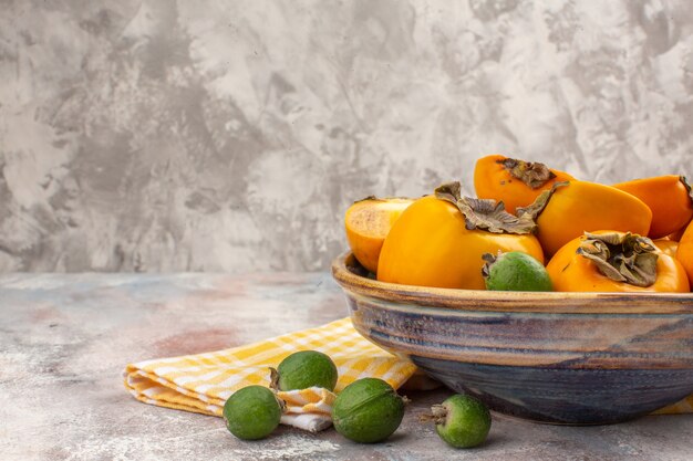 Front half view fresh persimmons in a bowl yellow kitchen towel feykhoas on nude free place