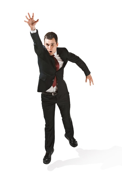 Above front portrait of businessman with serious face. Confident professional jumping in foreground of the camera. Diplomat on white studio background. Caucasian young man at studio