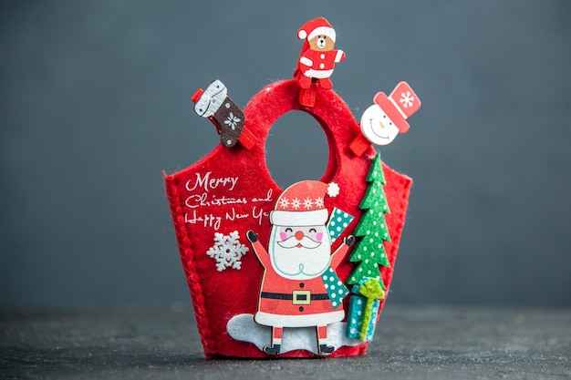 Vista laterale frontale dell'atmosfera natalizia con accessori decorativi e confezione regalo di capodanno su superficie scura