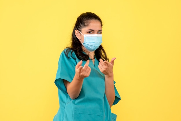 Front vie female doctor with mask pointing with fingers at front