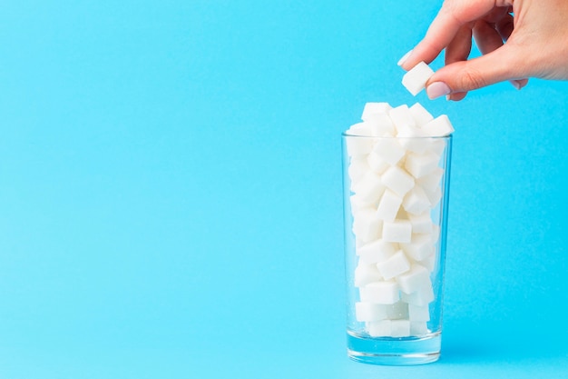 Front view of and adding sugar cube to glass with copy space