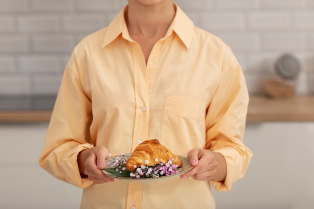 Front view adult holding plate with croissant