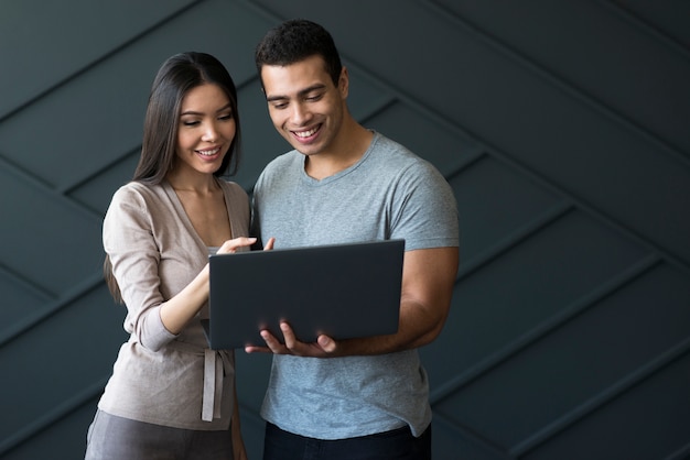 Front view adult male and woman holding a laptop