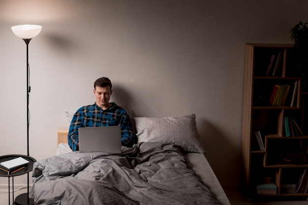 Front view adult male working from bed