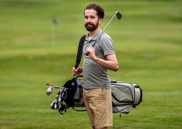 Вид спереди взрослый мужчина с клюшками для гольфа