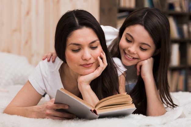 Front view adult woman and girl reading book