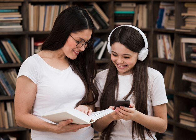 Front view adult woman with young girl at the library