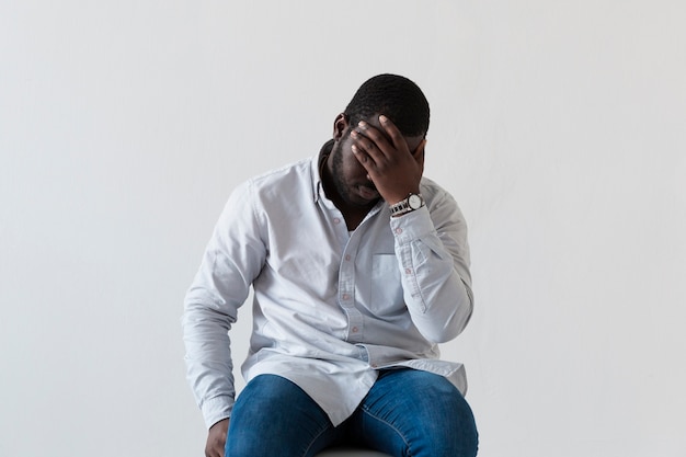 Free photo front view afro-american man covering his face