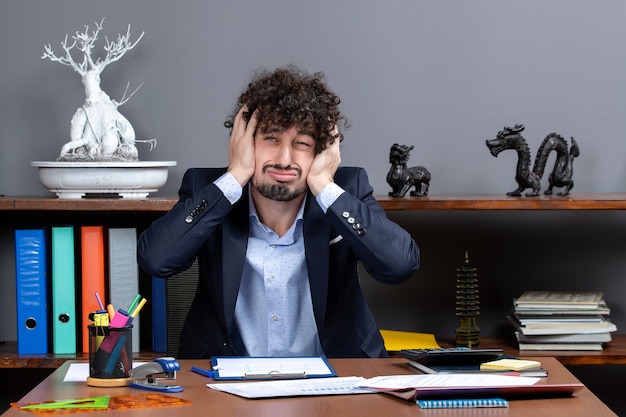 Foto gratuita vista frontale uomo d'affari agitato seduto alla scrivania che tiene la testa
