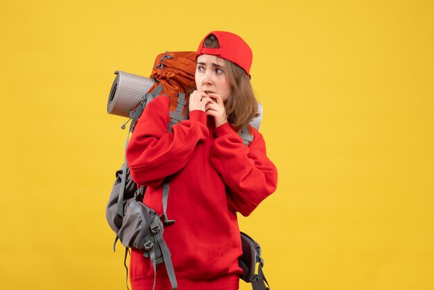 Front view agitated female traveler with backpack eating nails