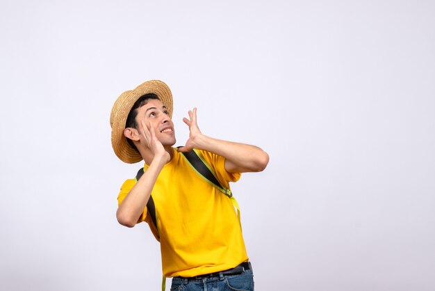 Взволнованный молодой человек в соломенной шляпе и желтой футболке, вид спереди
