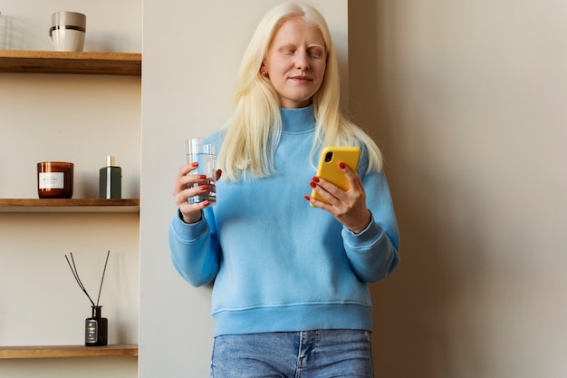 Free photo front view albino woman holding smartphone