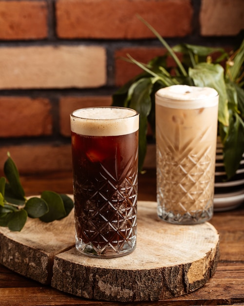 A front view alcohol drinks inside glasses on the brown wooden desk