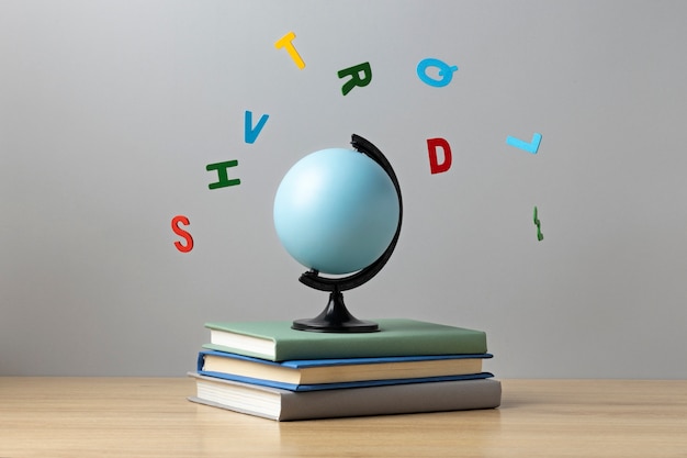 Front view of alphabet letters, stacked books and an earth globe for education day