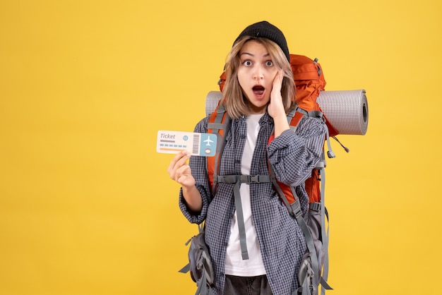 Front view of amazed traveler woman with backpack holding ticket