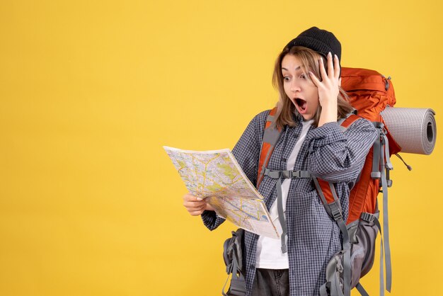 地図を見てバックパックと驚いた旅行者の女性の正面図