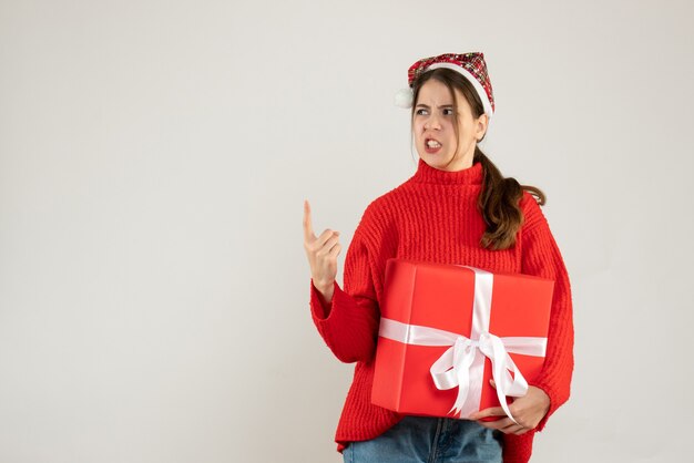 Front view angry girl with santa hat holding present standing