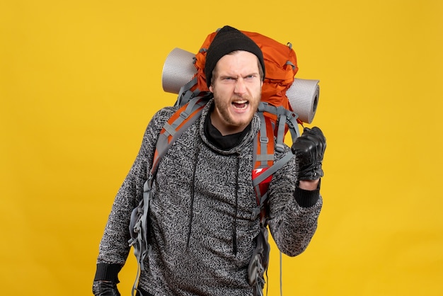 Front view of angry male hitchhiker with leather gloves and backpack showing punch