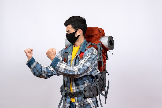 Front view angry young hiker with backpack and mask being ready to fight