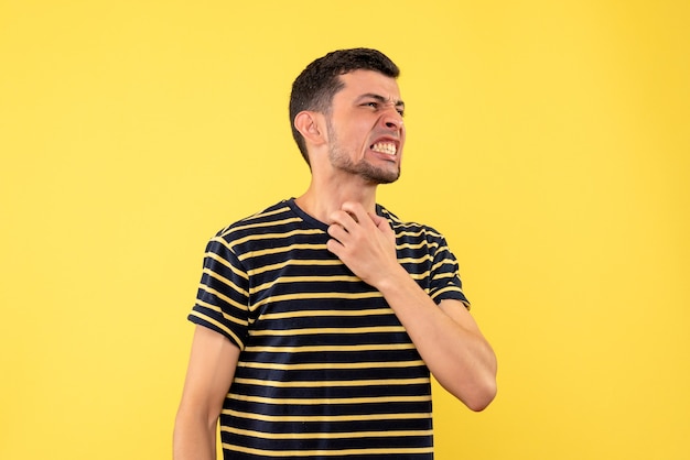 Front view angry young man in black and white striped t-shirt yellow isolated background