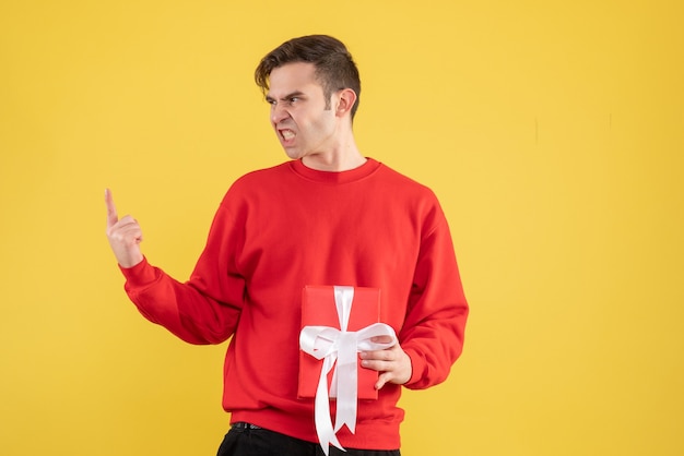 Front view angry young man with red sweater standing on yellow 