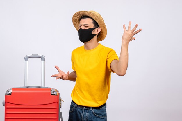 Front view angry young man with yellow t-shirt and red suitcase