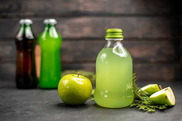 Front view apple juice in bottles lemonades apples wood board on wooden surface