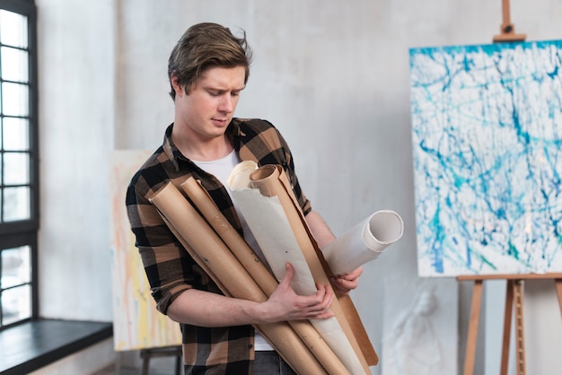 Free photo front view artsy man holding his paintings